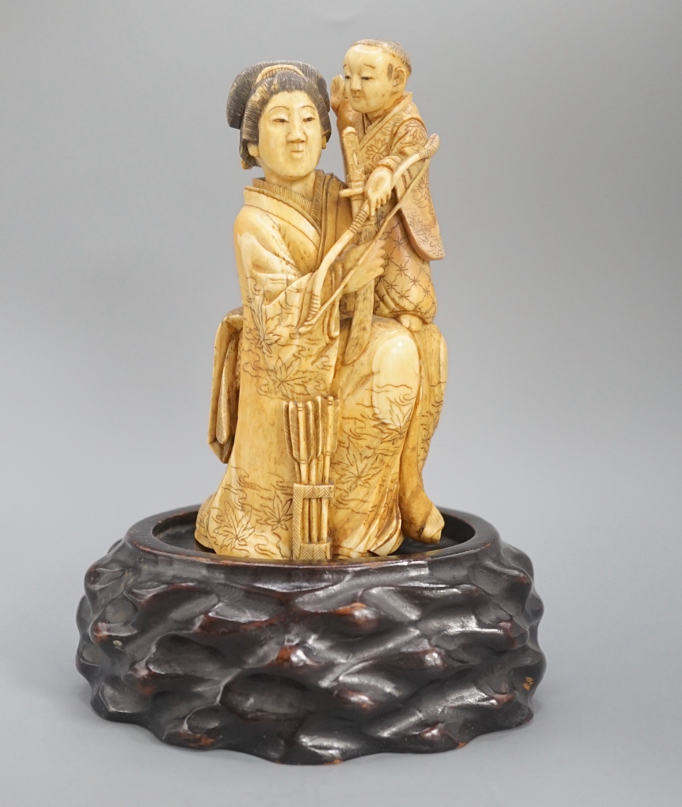 A Japanese ivory okimono of a lady holding a boy with a bow and arrow, Meiji period, restoration 12cm, wood stand